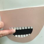 photo d'une illustration tactile représentant le bas d'un visage avec la bouche ouverte laissant voir et toucher deux rangées de dents