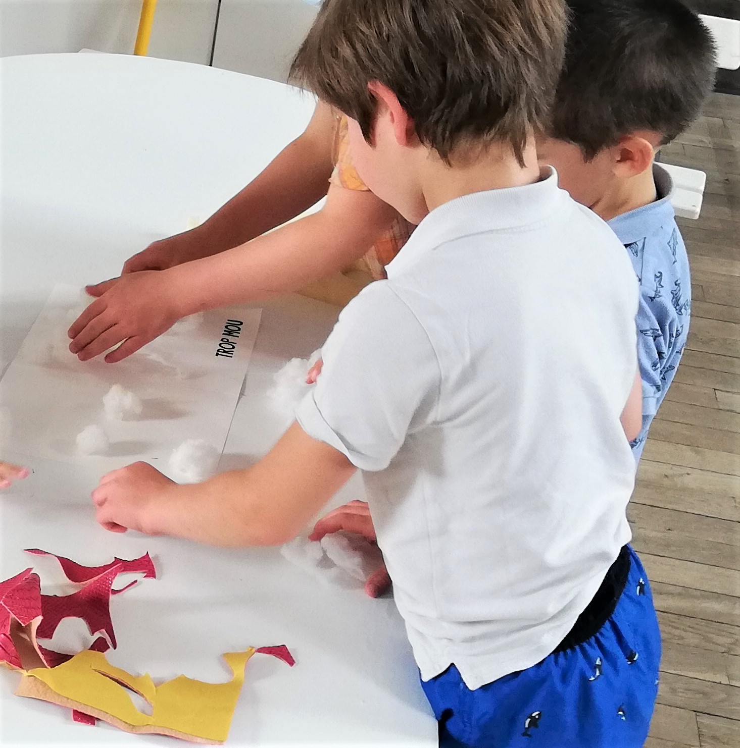 des enfants placent des matières sur une page vierge pour fabriquer un livre
