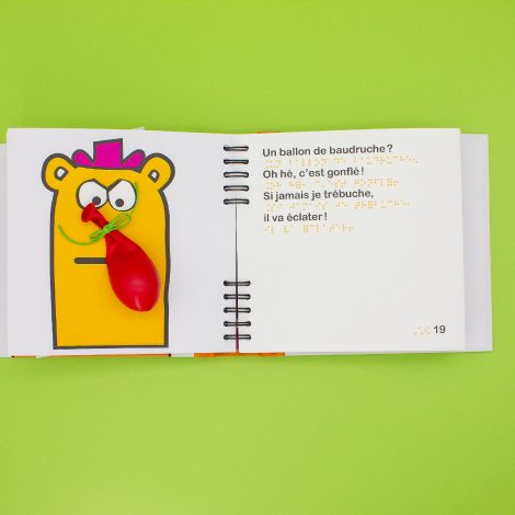 double page, personnage avec un ballon de baudruche à la place du nez et texte en braille sérigraphié coloré orange comme le personnage, texte en gros caractères