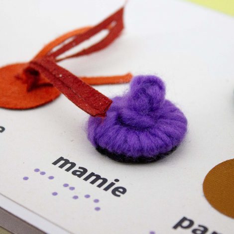mamie illustrée avec un chignon en laine violette ecriture braille et gros caractères