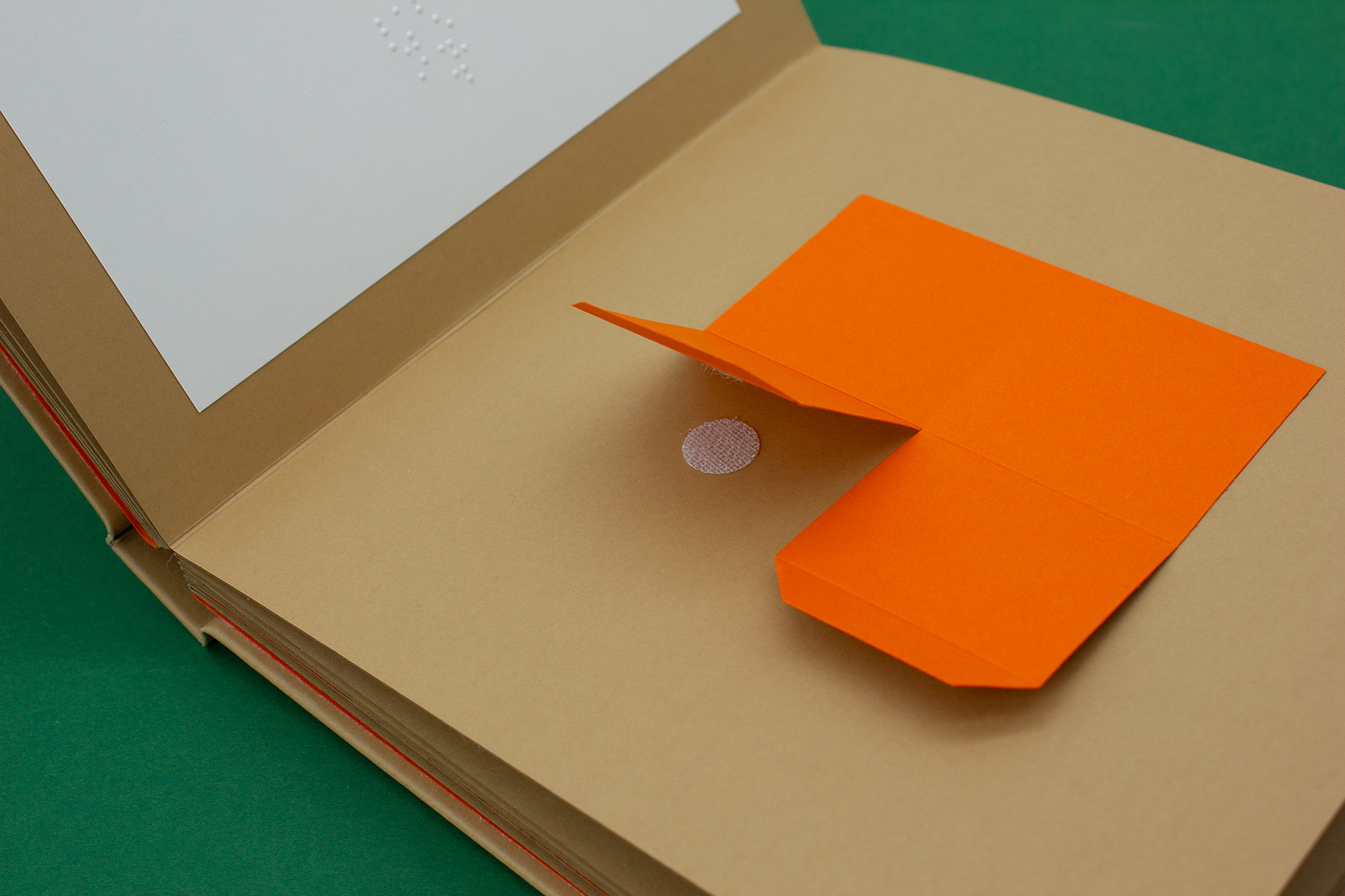 papier orange décollé par un velcro, texte en braille embossé