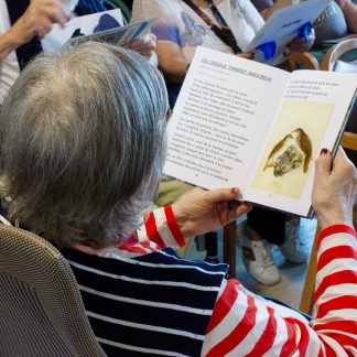 femme âgée qui lit un texte issu d'un coffret multisensoriel