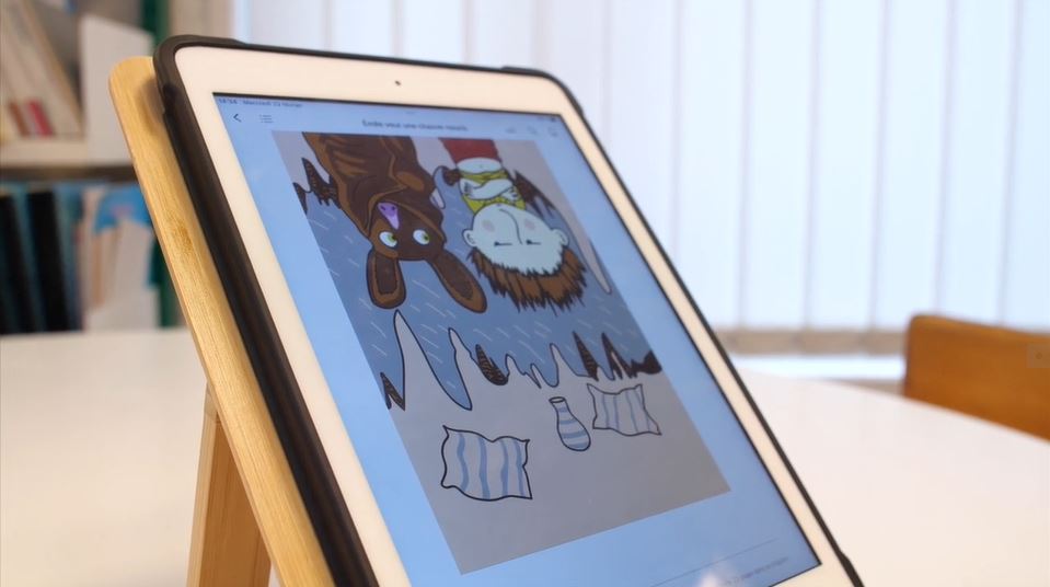 photo d'une tablette numérique avec à l'écran une illustration d'emile veut une chauve souris présentant une chauve-souris et un garçon cote à cote avec la tete en bas