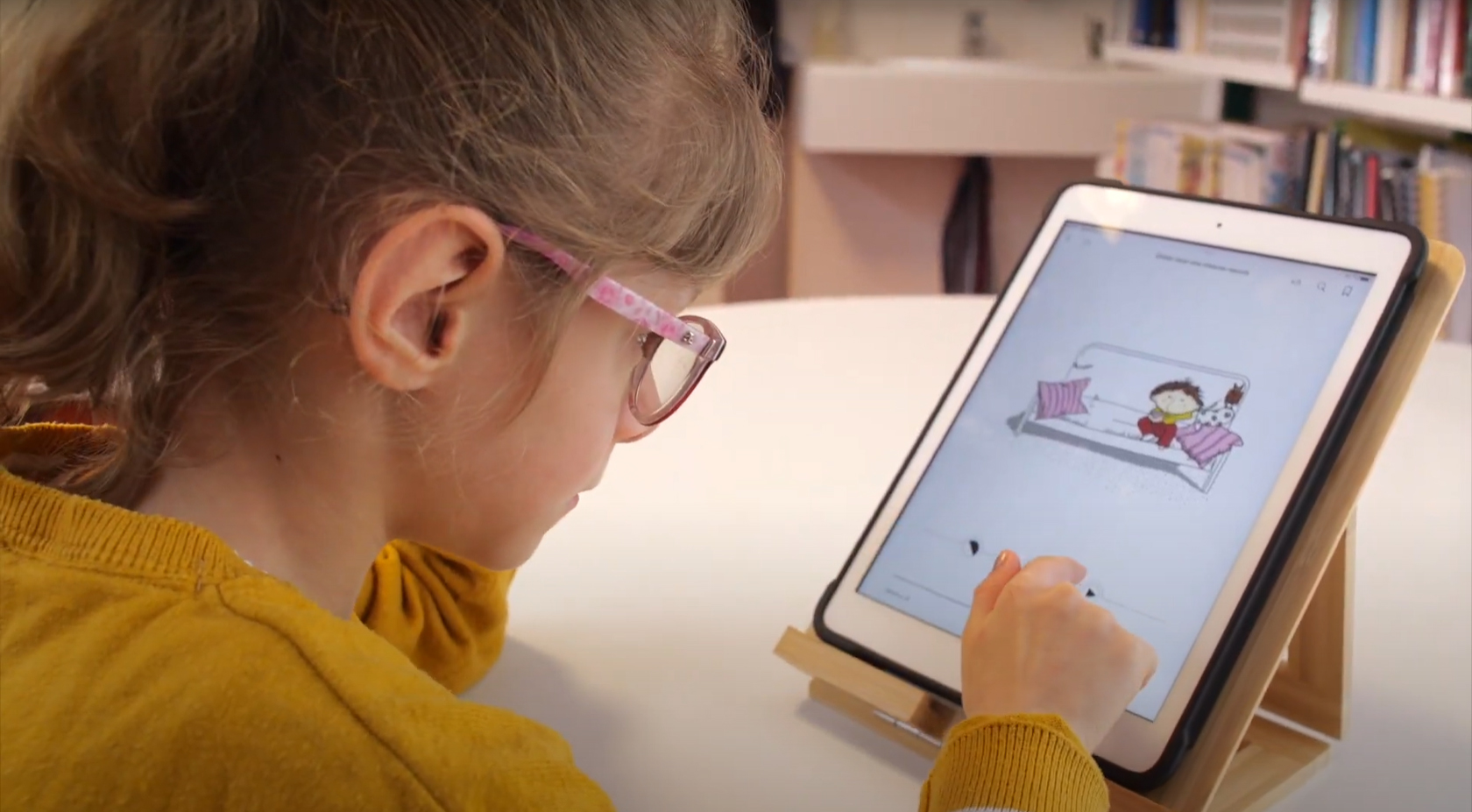 une petite fille lit un livre numérique sur une tablette