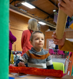 un enfant et des mains d'adultes manipulent la boîte sonore