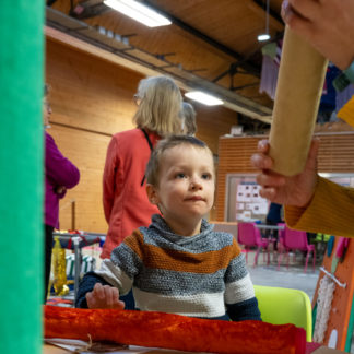 un enfant et des mains d'adultes manipulent la boîte sonore