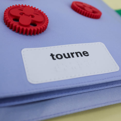"Tourne", deux rouages rouges cousus sur la page de luvre