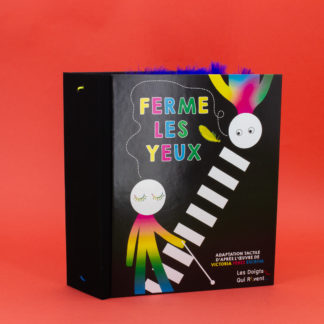 Livre tactile "Ferme les yeux". Il est très épais et de couleur noir. Sur la couverture il y a deux bonhommes multicolores dont un avec une canne blanche