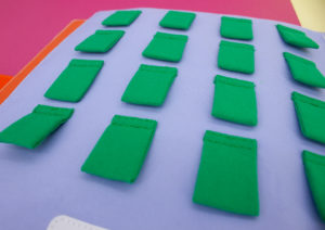 16 petits carrés verts découpé et cousu sur une page d'un livre