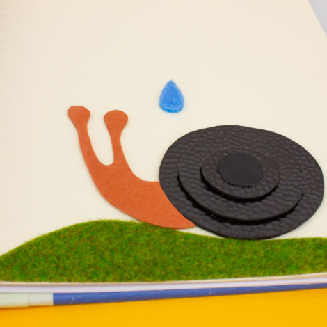 Page du livre avec une illustration tactile, un escargot qui reçoit une goutte sur lui