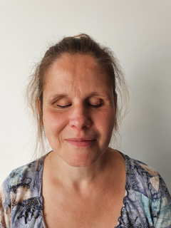 Photo d'Anne Chotin, cheveux chatains, blond attaché et un haut bleu avec des touches d'orange.