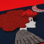 photo d'un détail d'une illustration tactile représentant l'un des personnages principaux : Léna avec ses cheveux rouge, une lune au dessus de la tête