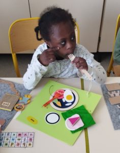 Une enfant joue avec l'illustration de la cantine, elle fait semblant de manger