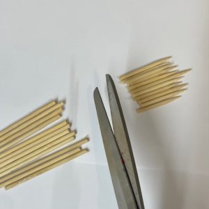 Des ciseaux coupent des pics en bois (pics à brochette)