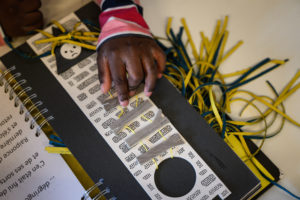 Un enfant en situation de handicap manipule un ouvrage illustre en braille