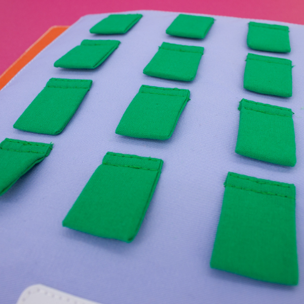 Illustration tactile de 12 petits carrés verts cousus sur le livre.