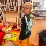 une enfant de l'IJA  porte sur son dos le livre tactile intitulé "mon cartable"  qui est présenté sous la forme d'un vrai cartable
